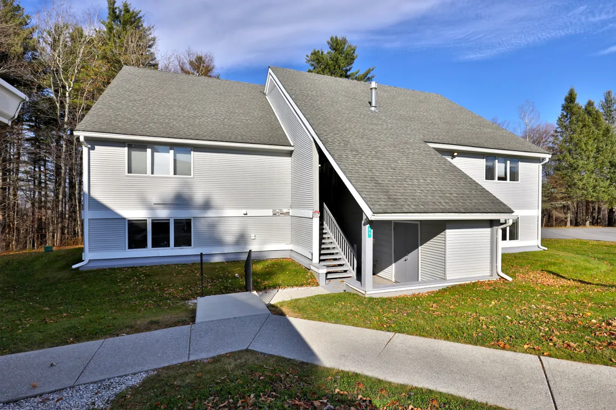 The photo features the property's inviting front entrance, including a staircase and manicured lawn. It conveys easy access for guests to come and go with their ski or snowboard gear, reinforcing the property's convenient ground-floor location referenced in the text.
